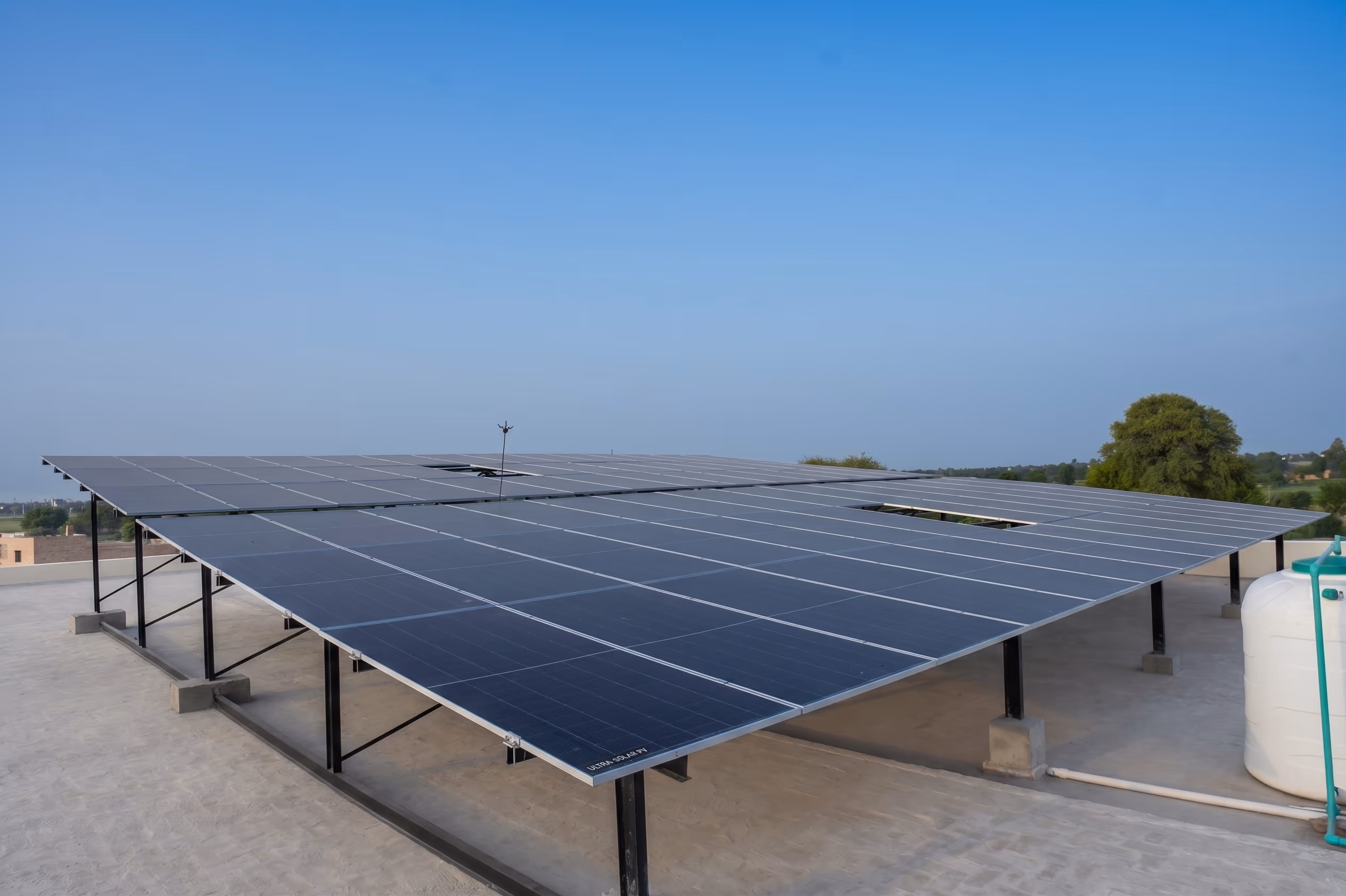 Elevated solar array spanning a flat rooftop under clear sky
